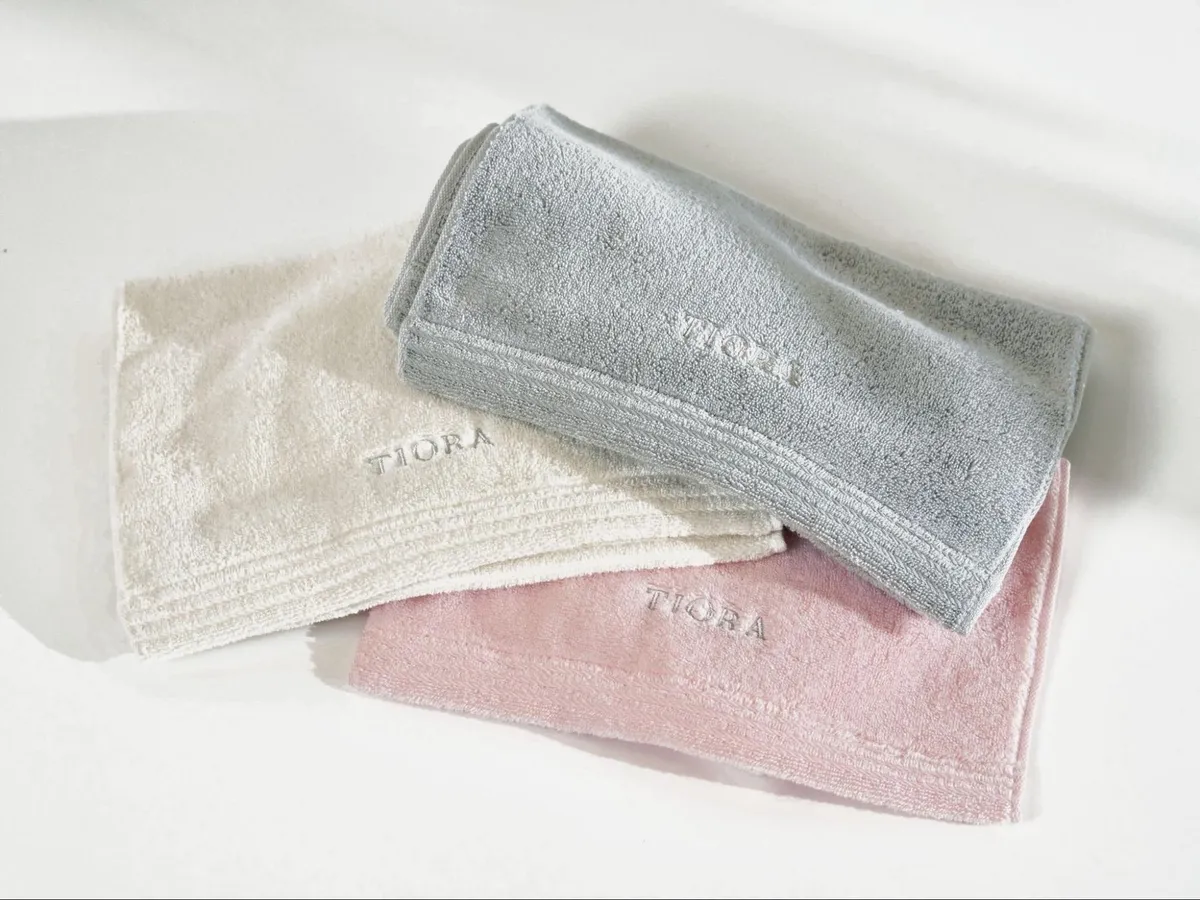 TIORAのロゴが刺繍されたアイボリー、グレー、ピンクのタオル